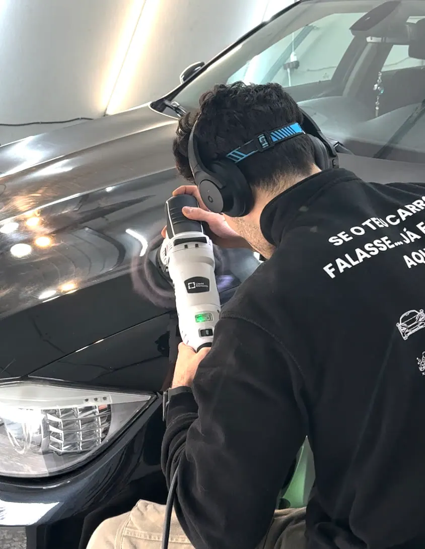 O Martim a polir o capô de um carro preto no estúdio