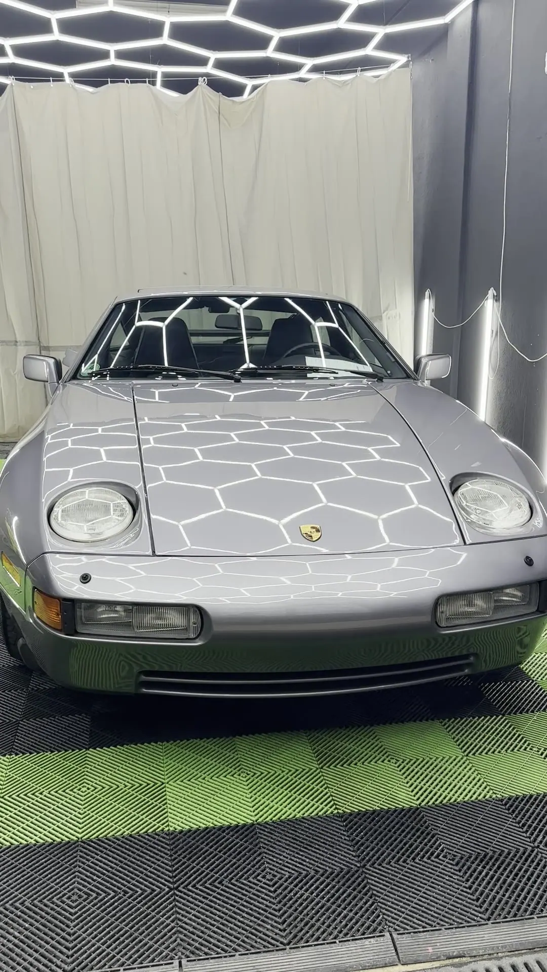 Porsche 928 S4 prateado debaixo das luzes hexagonais